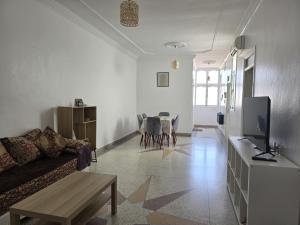 a living room with a couch and a table at KARAZ Homestay Grand appartement avec rooftop in Monte ʼArrouit