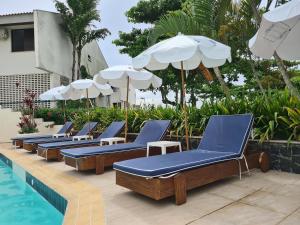 a row of lounge chairs and umbrellas next to a swimming pool at Hotel Praia Brava in Florianópolis