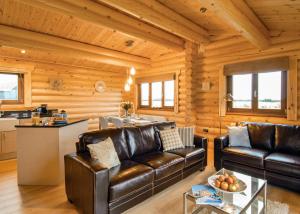 una sala de estar con muebles de cuero en una cabaña de madera en Laxfield Lodges, en Laxfield