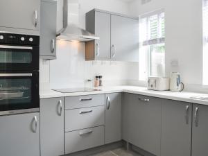 a white kitchen with white cabinets and a window at Rose And Jay House in Bridlington +15 photos