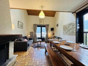 Una sala de estar con una mesa y una chimenea. en Spacieux Triplex 4 pièces, 7 couchages, proche pistes, parking, calme - FR-1-330F-74, en Le Monêtier-les-Bains