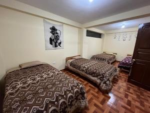 a bedroom with two beds and a picture on the wall at Hospedaje Catalina in Pisac