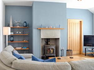 Una sala de estar con un sofá y una chimenea. en Eleanor Cottage, en Ballater