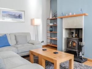 Una sala de estar con un sofá y una chimenea. en Eleanor Cottage, en Ballater