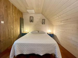 a bed in a wooden room with two lights on two tables at Gites la Rifflais - L'étang - vue sur étang privé in Langrolay