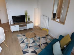 a living room with a blue couch and a table at Cosy Iris- T4 - Avec Balcon & Parking gratuit in Pau