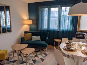 a living room with a blue couch and a table at Cosy Iris- T4 - Avec Balcon & Parking gratuit in Pau +23 photos