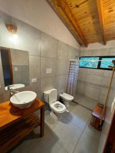a bathroom with a sink and a toilet and a mirror at PUERTO HOSTEL in El Hoyo