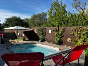 a swimming pool with two chairs and an umbrella at Villa Simone proche Uzes et pont du Gard in Blauzac