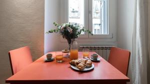 a red table with a plate of food and orange juice at Italianway - Tadino 1 B in Milan +19 photos