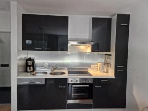 a kitchen with black cabinets and a stove top oven at NEU! Ferienwohnung Ankerplatz Hooksiel in Hooksiel