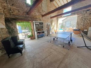a room with a ping pong table in a stone wall at La maison SPA, PISCINE et CLIMATISATION in Sainte-Vallière