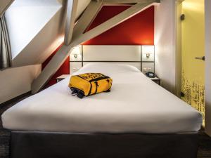 a yellow bag sitting on a bed in a room at Ibis Styles Strasbourg Centre Gare in Strasbourg +40 photos