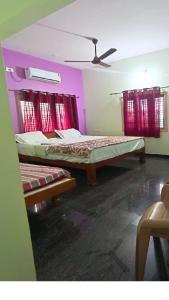 a bedroom with two beds and a ceiling fan at Harsha Home Stay in Hospet