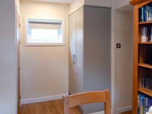 ein Zimmer mit einer Tür, einem Fenster und einem Bücherregal in der Unterkunft Sunnybank Cottage in Inveralligin