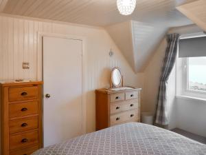 ein Schlafzimmer mit einem Bett, einer Kommode und einem Spiegel in der Unterkunft Sunnybank Cottage in Inveralligin