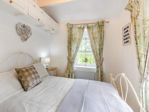 a bedroom with a white bed and a window at Holme House Cottage in Oakworth