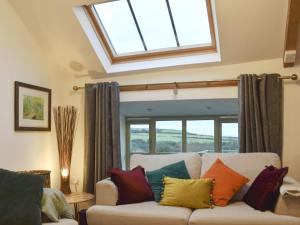 a living room with a white couch with colorful pillows at Ty Cam - Of5 in Aberdaron