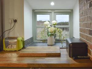 a vase of flowers in a room with a window at Ty Cam - Of5 in Aberdaron
