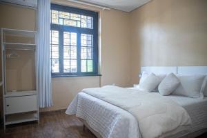 ein Schlafzimmer mit einem großen weißen Bett mit einem Fenster in der Unterkunft Casa térrea geminada aconchegante AV3402 in Higienópolis