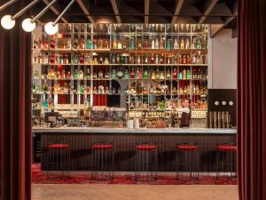 a bar with red stools in front of a counter at Hôtel Saint Christophe Aix en Provence Centre Ville by Germain Collection in Aix-en-Provence