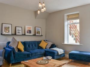 St Georges Cottage في هولمفيرث: غرفة معيشة مع أريكة زرقاء وطاولة