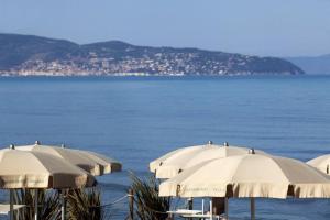 a row of white umbrellas on a beach next to the water at Happy Sea Home - Bilocale Angolo Cottura 4 pax in Albinia