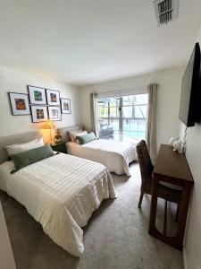 a bedroom with two beds and a desk and a window at Coastal Escape in Bonita Springs
