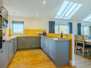 una cucina con armadi grigi, tavolo e sedie di Invernahyle Cottage ad Acharra