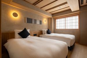 duas camas em um quarto com duas janelas em soyo-ne kyoto sanjo em Quioto