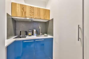 a kitchen with blue cabinets and a sink at Charmant studio au coeur des Batignolles in Paris