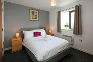 a bedroom with a large white bed with pink pillows at Albion Street Apartments in Wolverhampton