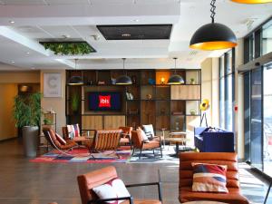a lobby with chairs and a tv in a building at ibis Beauvais Aéroport in Beauvais