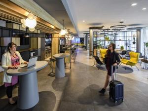 two women with luggage in an office with a table and a laptop at ibis Hotel Muenchen City West in Munich