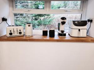 three coffee machines sitting on a counter next to a window at Riverside Cottage in Larkhall