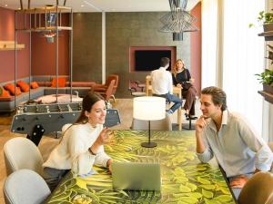 a group of people sitting around a table with a laptop at Aparthotel Adagio Muenchen City in Munich