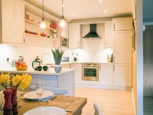 Una cocina con gabinetes blancos y una mesa de madera. en Swallows Nest, en Windermere