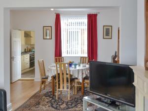 una sala da pranzo con un tavolo e una televisione di Dolphin Cottage a Newbiggin-by-the-Sea