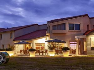 una casa con mesas y sombrillas en un patio en ibis Styles Cholet, en Cholet