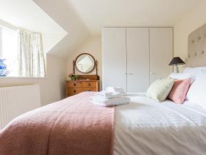 a bedroom with a large bed with pink sheets and a mirror at Hungate Garden Cottage in Pickering