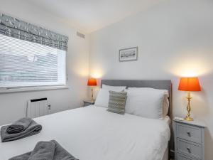 ein Schlafzimmer mit einem weißen Bett und einem Fenster in der Unterkunft Arthurs Den - Cottage in Brixham