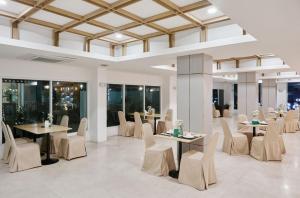 a dining room with tables and chairs and windows at Sunday Platinum Suites in Bangkok