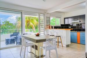 a kitchen with a table and chairs and a large window at Kay Ticole in Le Robert +4 photos