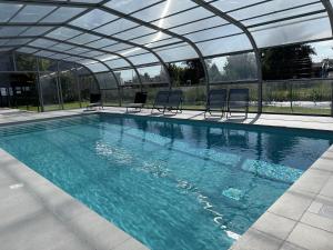a swimming pool with chairs and a glass ceiling at ibis Pontorson Baie Du Mont Saint Michel in Saint-Georges-de-Gréhaigne
