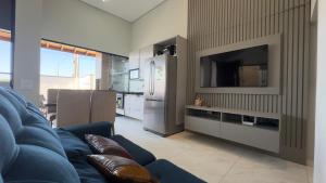 a living room with a blue couch and a television at Casa Moderna para Familias com Piscina Churrasqueira Wi-Fi e Ar Condicionado in Peruíbe