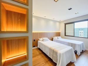 two beds in a room with a window at Cobertura Pé na Areia - Enxoval Completo Riviera in Riviera de São Lourenço +34 photos