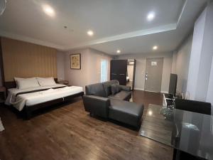 a bedroom with a bed and a couch and a chair at Sunday Platinum Suites in Bangkok