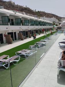 a row of lounge chairs and tables on a building at Apartamentos Florida Gran Canaria Adults Only in Puerto Rico de Gran Canaria
