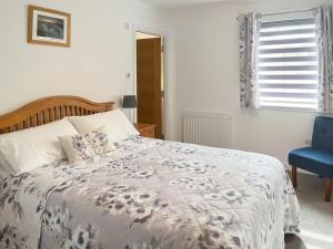 a bedroom with a bed and a blue chair at No 8 Cottage in Aviemore