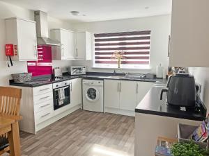 a kitchen with white cabinets and a washing machine at No 8 Cottage in Aviemore
